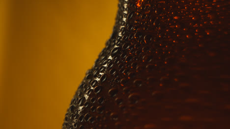 Macro-Shot-Of-Condensation-Droplets-On-Revolving-Bottle-Of-Cold-Beer-Or-Soft-Drinks-Against-Yellow-Background-1